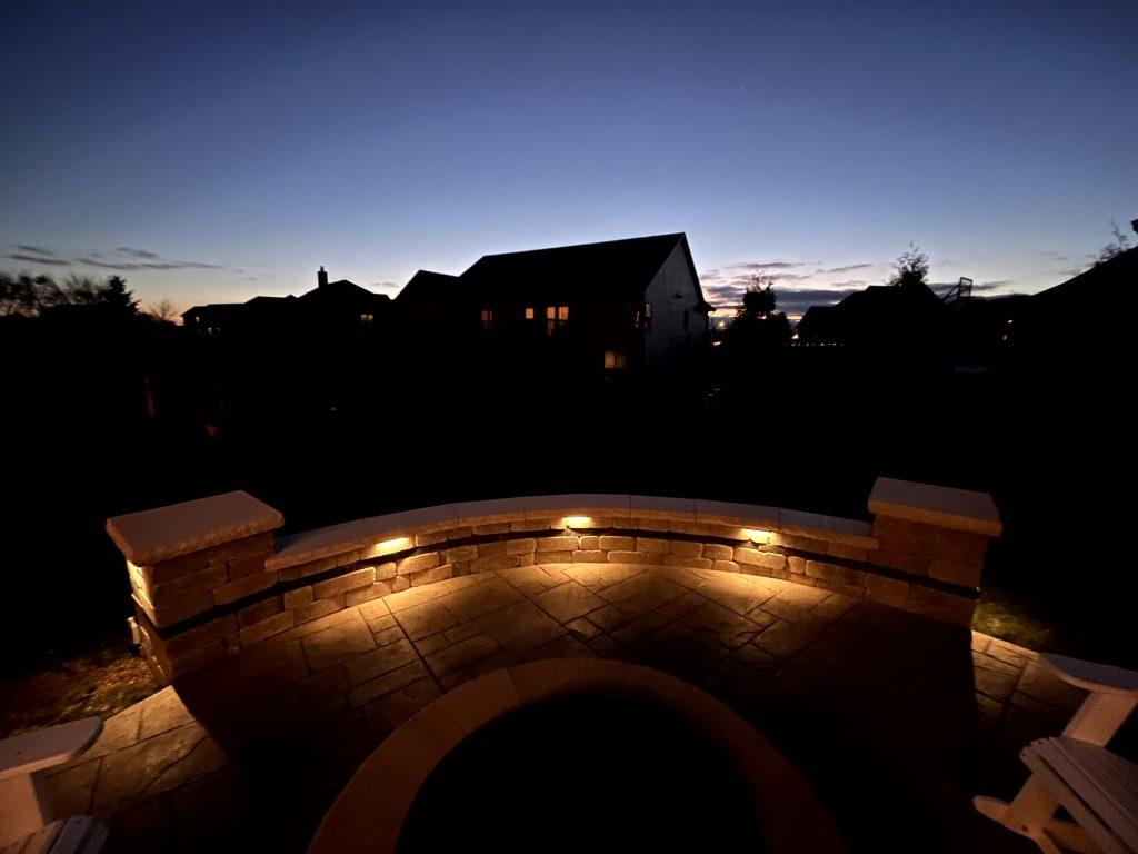 Integrated lighting along a curved seat wall and patio at dusk