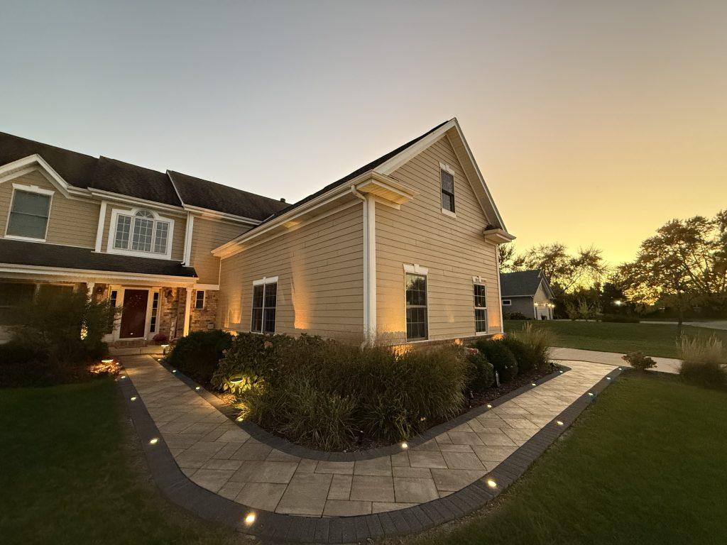 Path lights and exterior accent lighting around a landscape project at dusk